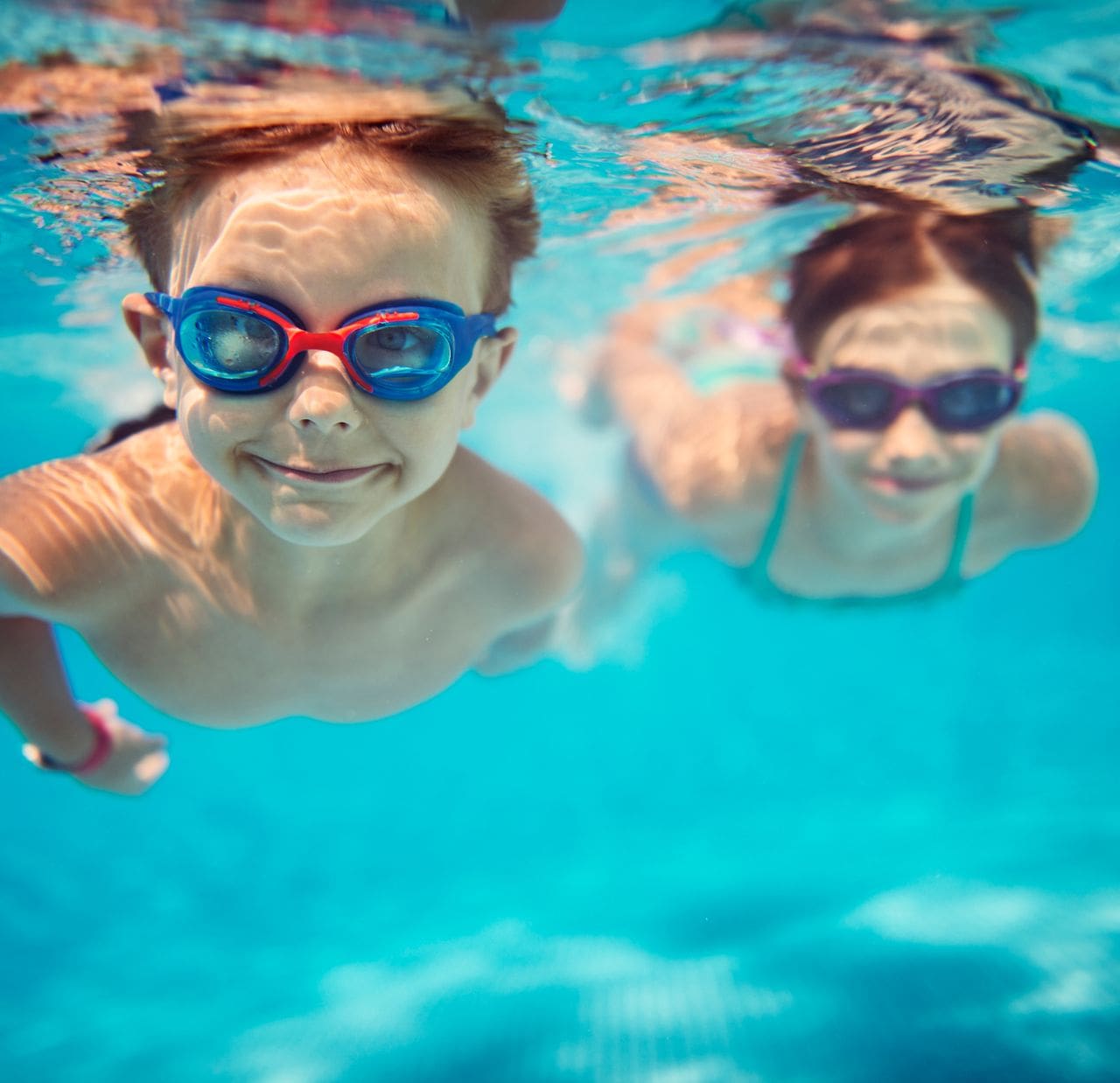 2 children swim underwater with goggles