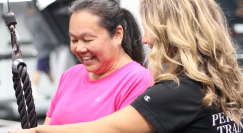 woman certified personal trainer walking through a strength training exercise with a female client