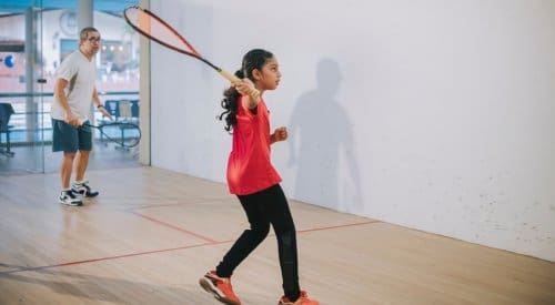 a young girl practices her racquetball swing during a racquetball lesson in a montrose fitness center
