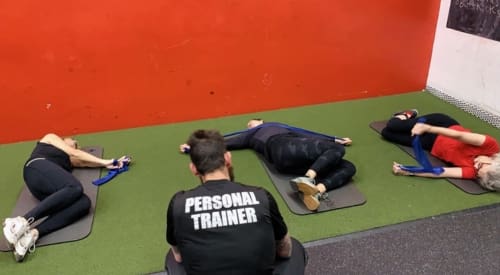 gym members work with a trainer during a small group training session at an athletic club near me